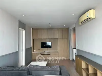 Modern living room with built-in TV unit and air conditioning, featuring a cozy sofa and sleek wooden cabinetry.