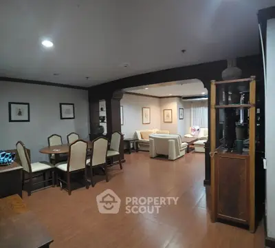Spacious living and dining area with elegant furniture and wooden flooring.