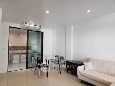 Modern living room with glass dining table and view into sleek kitchen