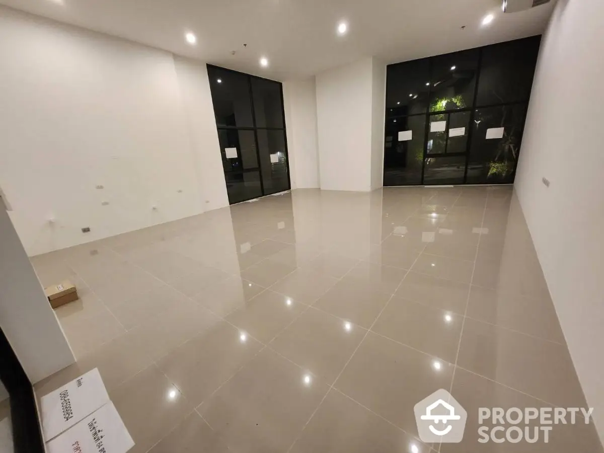 Spacious empty room with large windows and glossy tiled floor