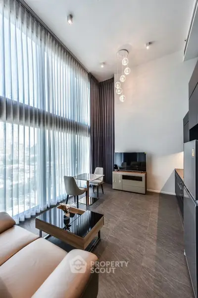 Modern living room with high ceilings, large windows, and stylish furniture in a contemporary apartment.