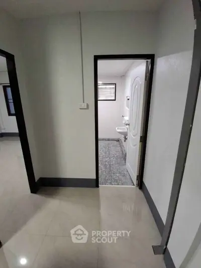 Spacious hallway leading to a modern bathroom with sleek fixtures.