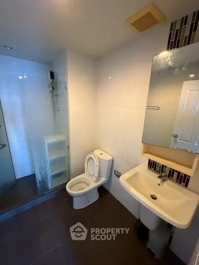 Modern bathroom with glass shower, toilet, and sink in a sleek design.