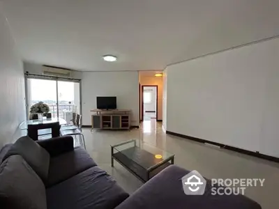 Spacious living room with modern furniture and large windows offering city views.