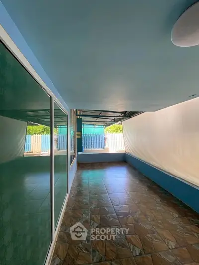 Spacious covered patio with tiled flooring and glass doors, perfect for outdoor relaxation.