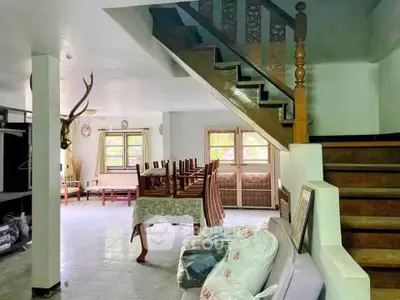 Spacious living room with wooden staircase and natural light, ideal for family gatherings.