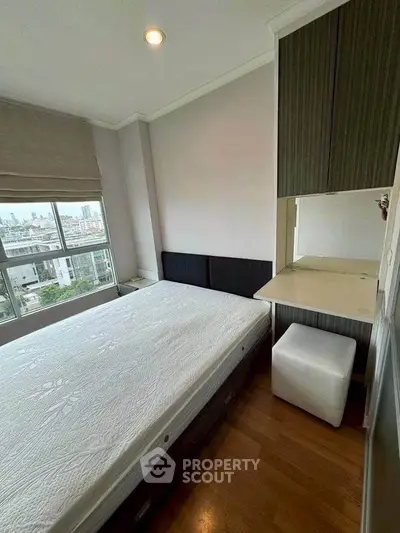 Modern bedroom with large window and built-in storage, offering city views and natural light.