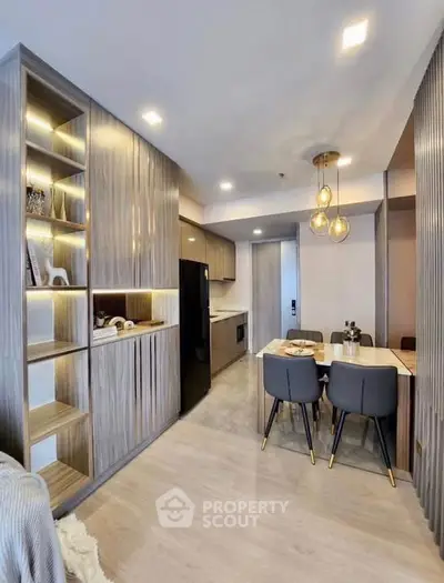 Modern open-layout kitchen and dining area with stylish lighting and wooden cabinetry.