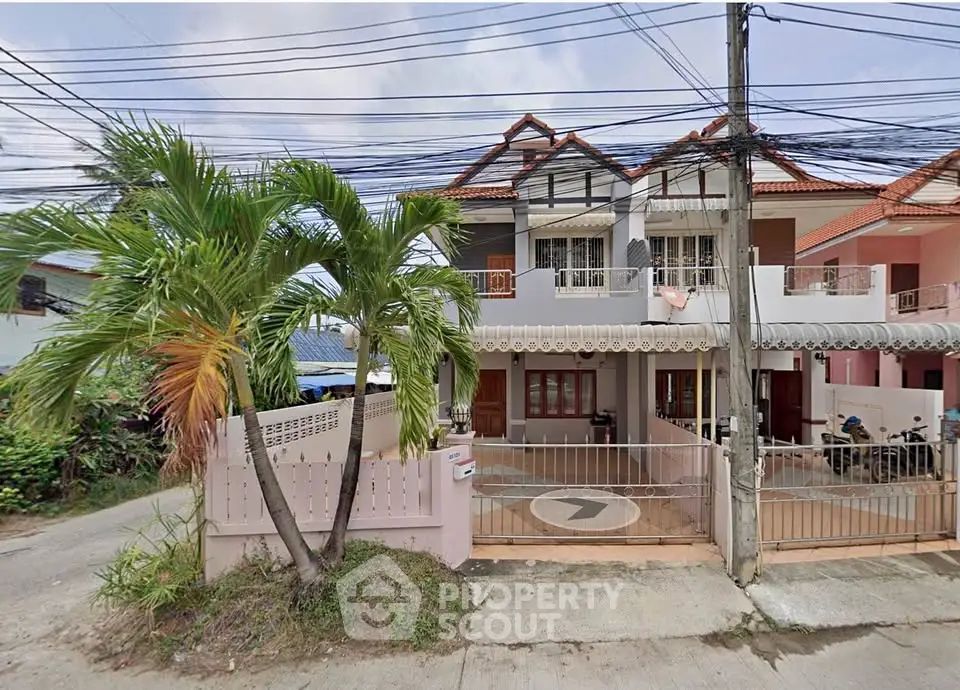 Charming suburban house with palm tree and gated entrance, perfect for family living.