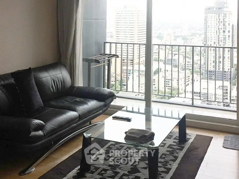 Modern living room with sleek black sofa and glass coffee table, offering a stunning city view from the balcony.