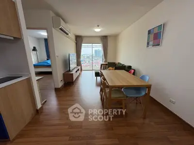 Spacious living room with modern decor and city view, featuring wooden flooring and colorful dining chairs.