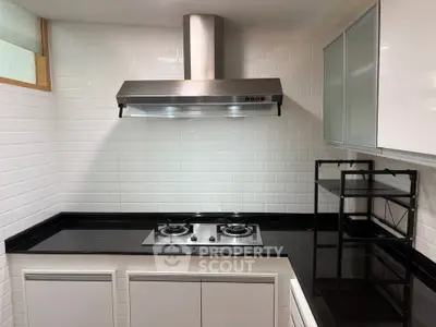 Modern kitchen with sleek gas stove and black countertops in stylish apartment.