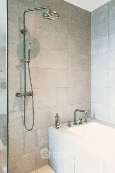 Modern bathroom with sleek shower and bathtub in elegant tile setting.