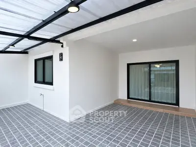 Modern covered patio with sleek tiled flooring and large sliding glass doors.