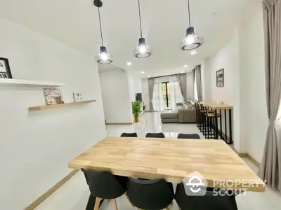 Modern open-plan living and dining area with stylish lighting and natural wood accents.