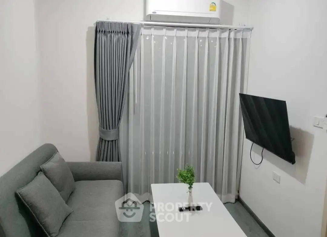 Modern living room with sleek gray sofa, wall-mounted TV, and air conditioning, perfect for cozy relaxation.