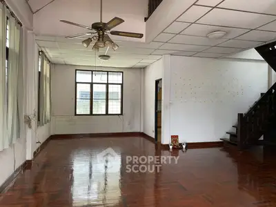 Spacious living room with wooden flooring and ceiling fan in a bright home.