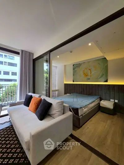 Modern studio apartment with cozy living area and large windows offering natural light and a view.