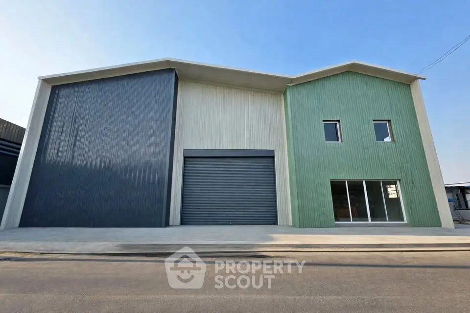 Modern industrial warehouse with large roller doors and green facade