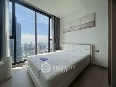 Modern bedroom with floor-to-ceiling windows offering stunning city views.