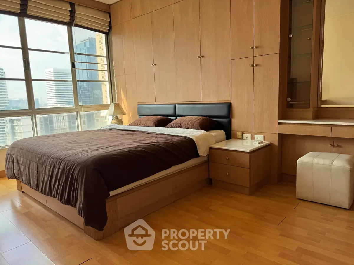 Spacious bedroom with city view and elegant wooden furnishings