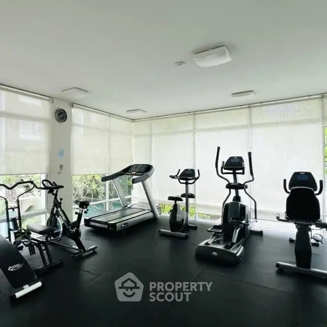 Modern gym with exercise equipment and natural light in a residential building.