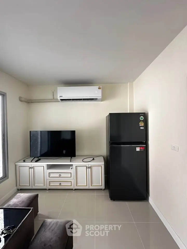 Modern living room with sleek black fridge and mounted TV, perfect for contemporary urban living.