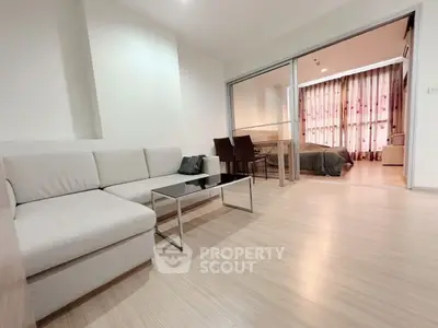 Modern living room with sleek furniture and open layout leading to bedroom.