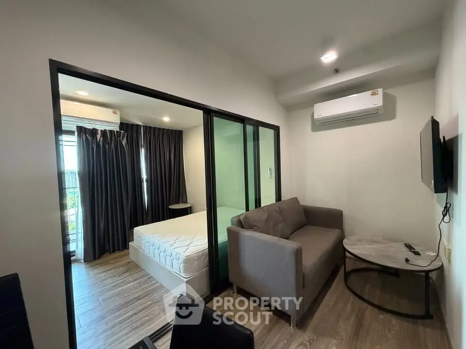 Modern studio apartment with glass partition, cozy sofa, and air conditioning.