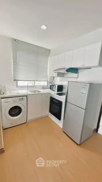 Modern kitchen with washing machine, oven, and fridge in a compact layout.