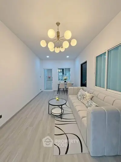 Modern living room with elegant chandelier and cozy seating area, perfect for relaxation and entertaining.