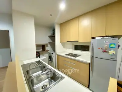 Modern kitchen with sleek cabinets, double sink, and appliances including fridge and washing machine.