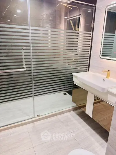 Modern bathroom with glass shower and sleek vanity in luxury apartment.