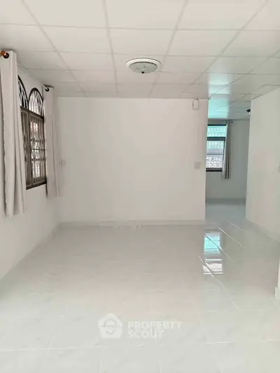 Spacious empty room with tiled flooring and large windows, ideal for customization.
