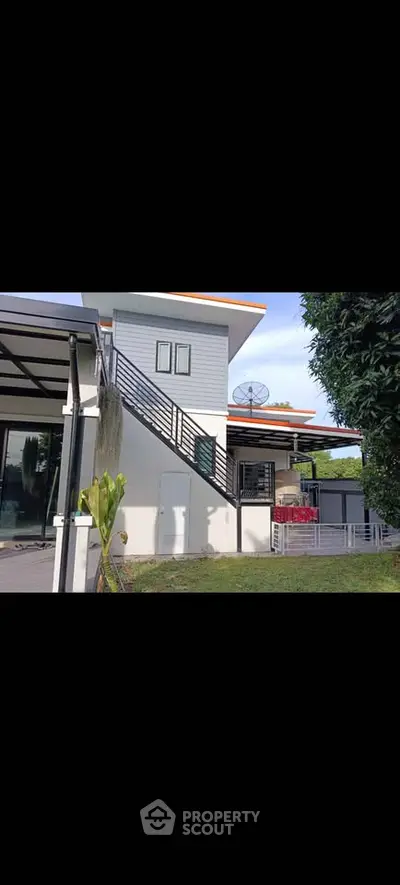 Modern two-story house with sleek exterior and lush garden, featuring a stylish staircase and contemporary design.