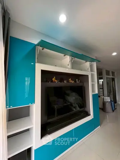 Modern living room with sleek blue and white entertainment unit and large TV.