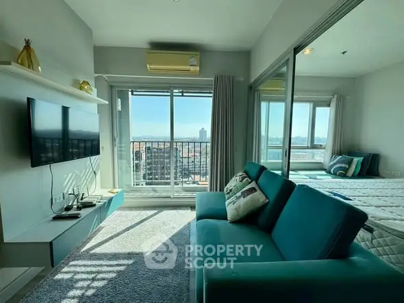 Modern living room with balcony and city view, featuring sleek furniture and abundant natural light.