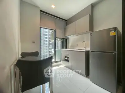 Modern kitchen with sleek cabinetry and stainless steel fridge in high-rise apartment.