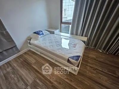 Modern bedroom with wooden flooring and large window, featuring a minimalist bed and elegant curtains.