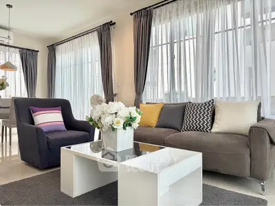 Elegant living room with modern decor, large windows, and stylish furniture, perfect for relaxation and entertaining.