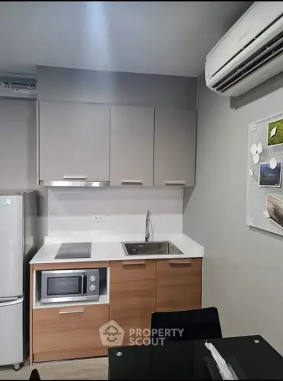 Modern compact kitchen with sleek cabinetry and built-in appliances in a stylish apartment.