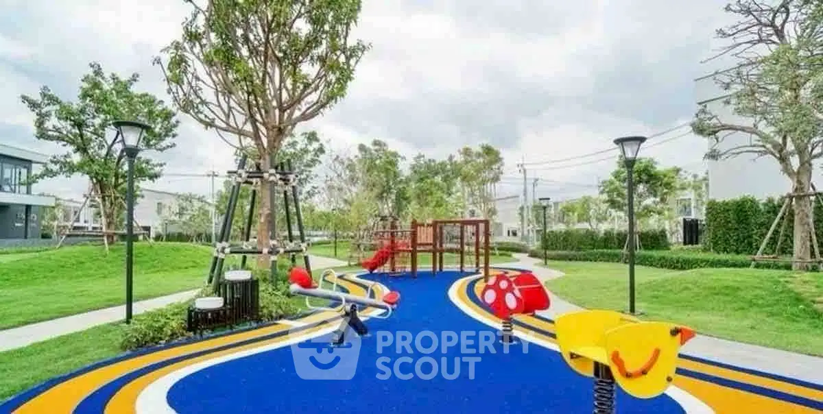 Vibrant playground in modern residential community with lush greenery and colorful equipment.