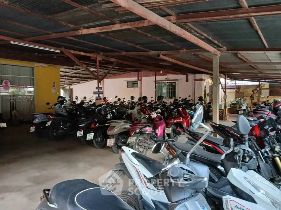 Spacious covered parking area with numerous motorbikes, ideal for urban living convenience.