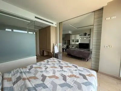 Modern bedroom with open layout to living area, featuring stylish decor and ample natural light.