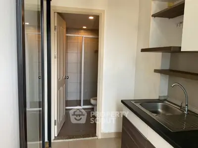 Compact apartment interior with kitchenette and bathroom view, featuring modern fixtures and efficient layout.
