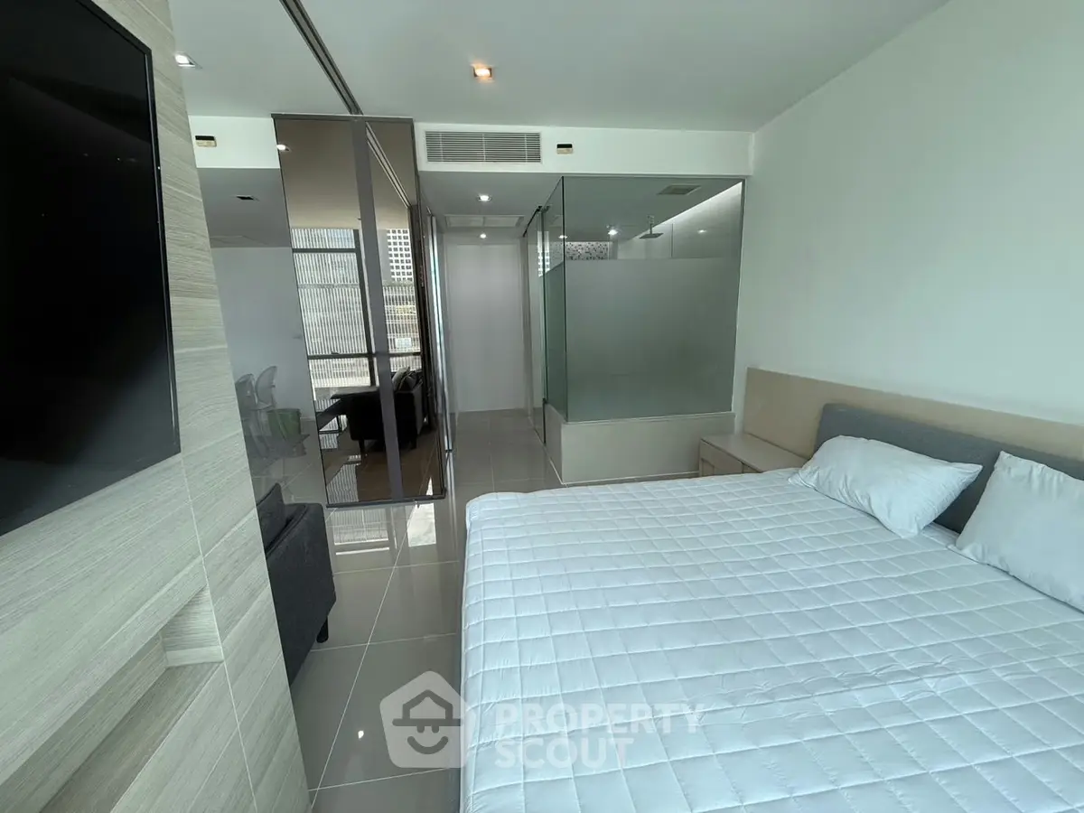 Modern bedroom with glass partition and sleek design in a high-rise apartment.