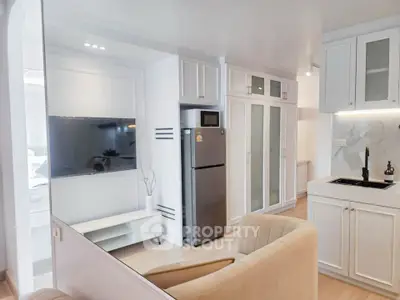 Modern open-plan living room with sleek kitchen and stainless steel fridge