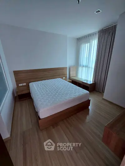 Modern bedroom with wooden flooring and large window, featuring a comfortable bed and stylish side tables.