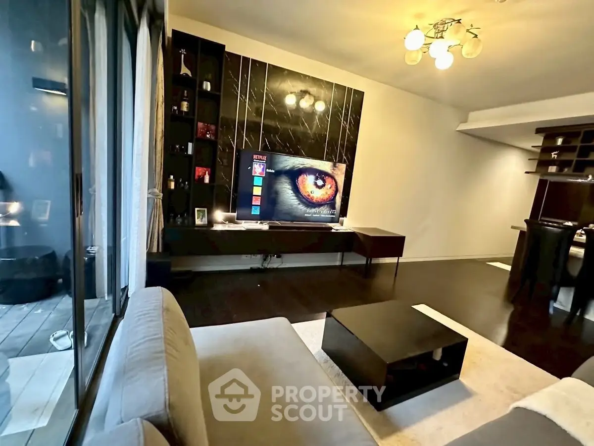 Modern living room with sleek furniture and large TV, featuring elegant lighting and dark wood flooring.