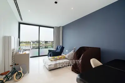 Modern living room with large window offering serene water view, featuring stylish furniture and minimalist decor.